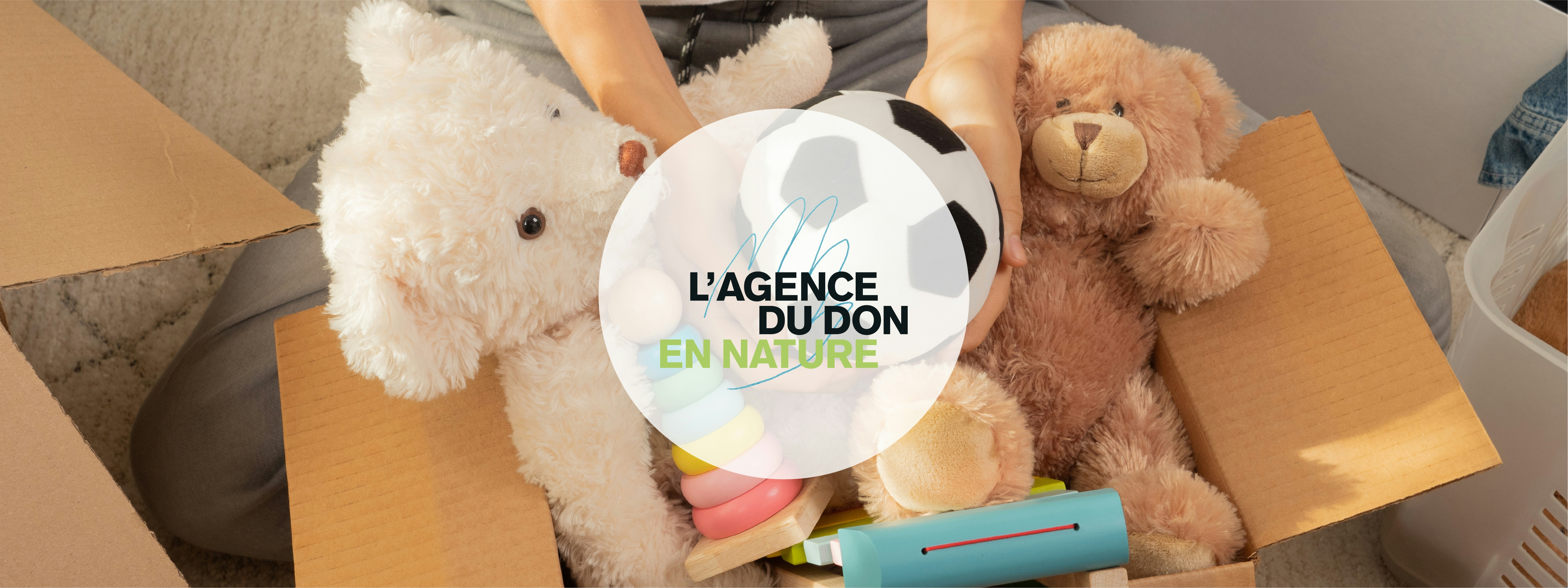 a carton remplis de peluches et jouet derrière le logo de l'Agence du Don en Nature.