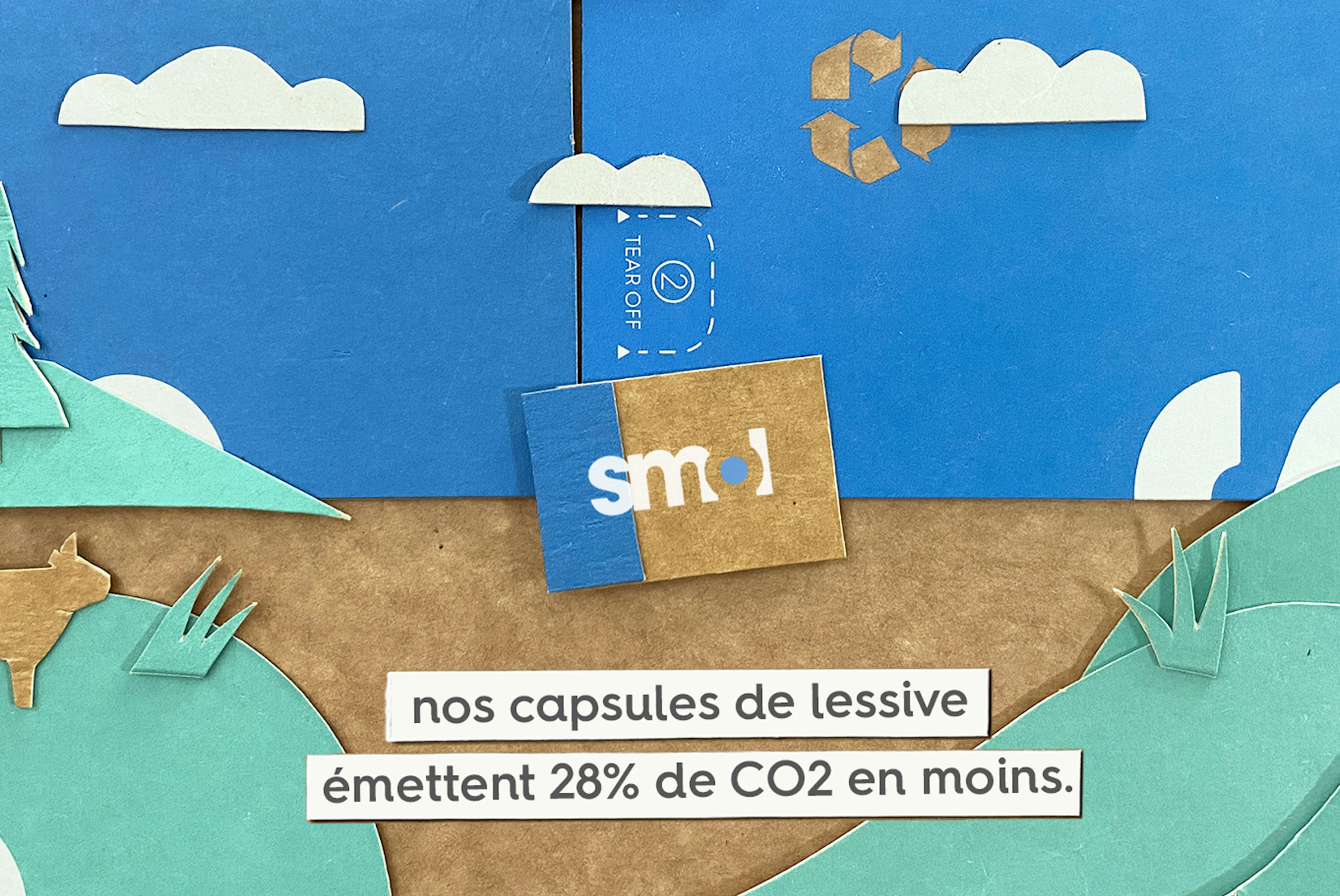 un paysage recréé à partir de morceaux de carton avec le texte « nos capsules de lessive émettent 28 % de CO2 en moins. »