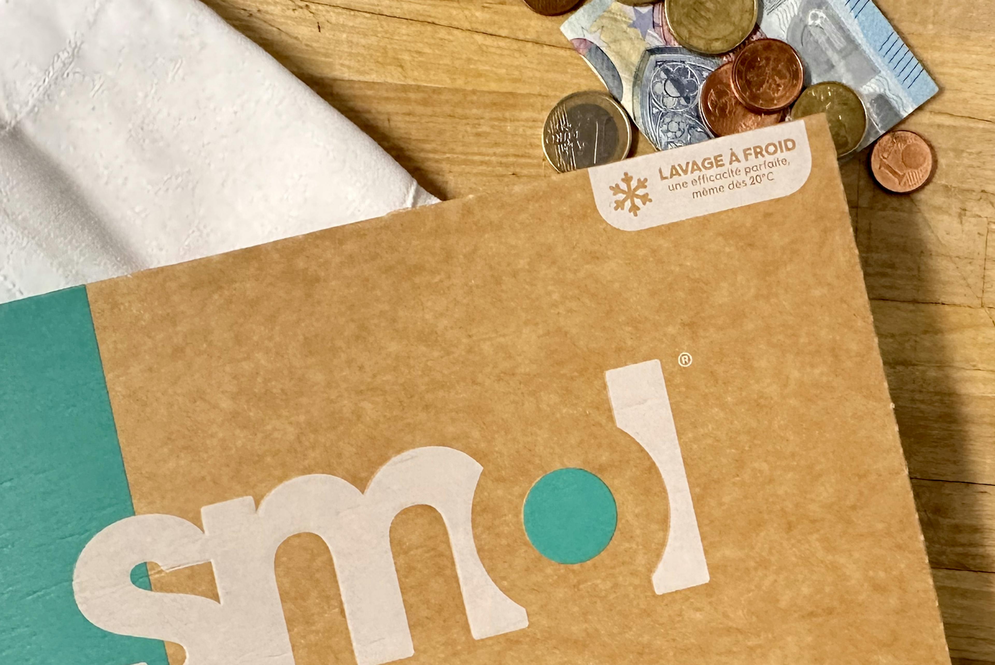 un pack de lessive smol à côté de pièces en euros