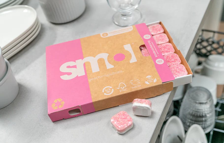 eine halboffene Packung smol Geschirrspültabs auf einer Küchenarbeitsplatte über einem geöffneten Geschirrspüler