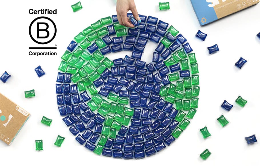 ein aus grünen und blauen smol Kapseln gelegter Globus, daneben einige verstreute Kapseln und das B Corp Logo
