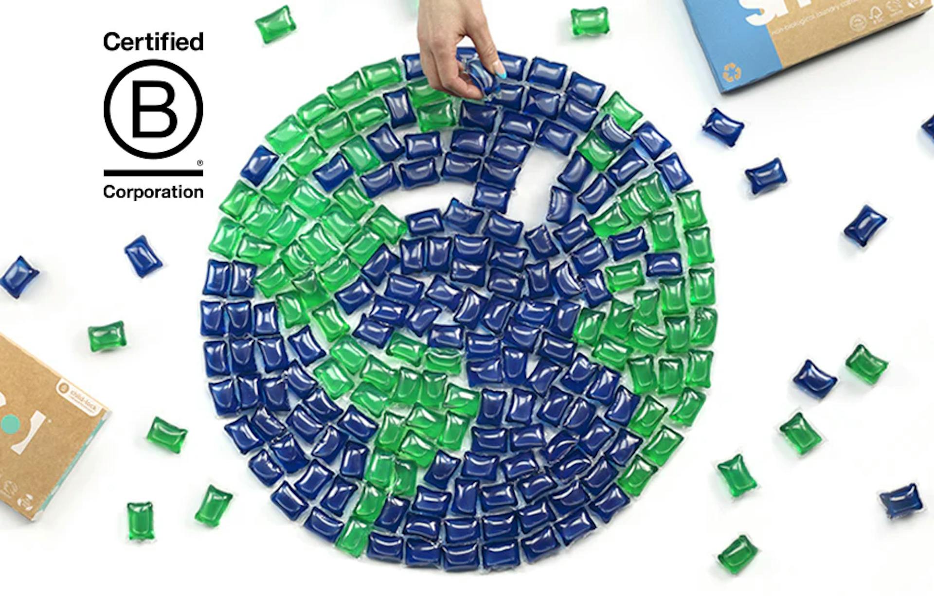 ein aus grünen und blauen smol Kapseln gelegter Globus, daneben einige verstreute Kapseln und das B Corp Logo