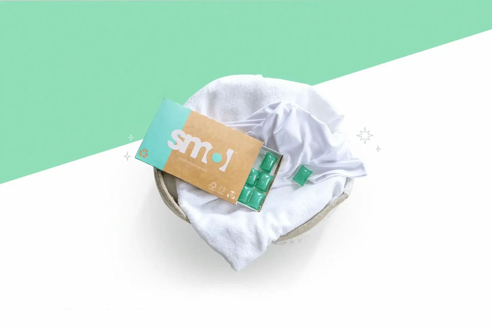 eine Animation, die eine smol Waschmittelpackung auf einem gefüllten Wäschekorb zeigt. Die Farbe der Packung, der Kapseln und des Hintergrunds wechselt von grau zu grün