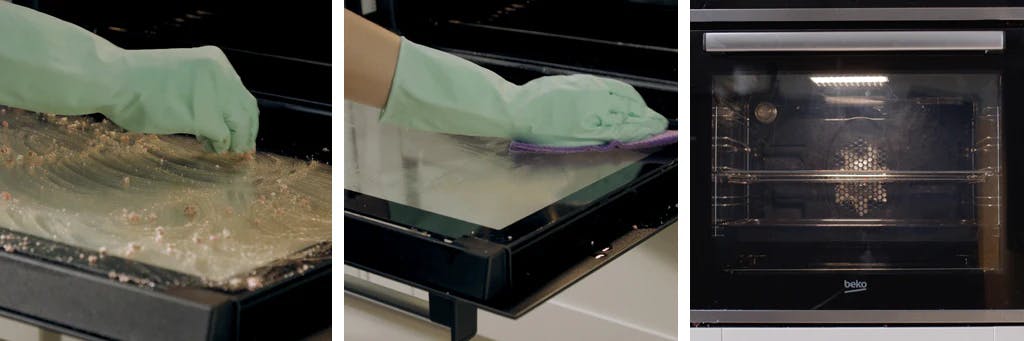 hands wearing rubber gloves rubbing dishwasher tablet onto glass oven door and then cleaning away with a damp cloth