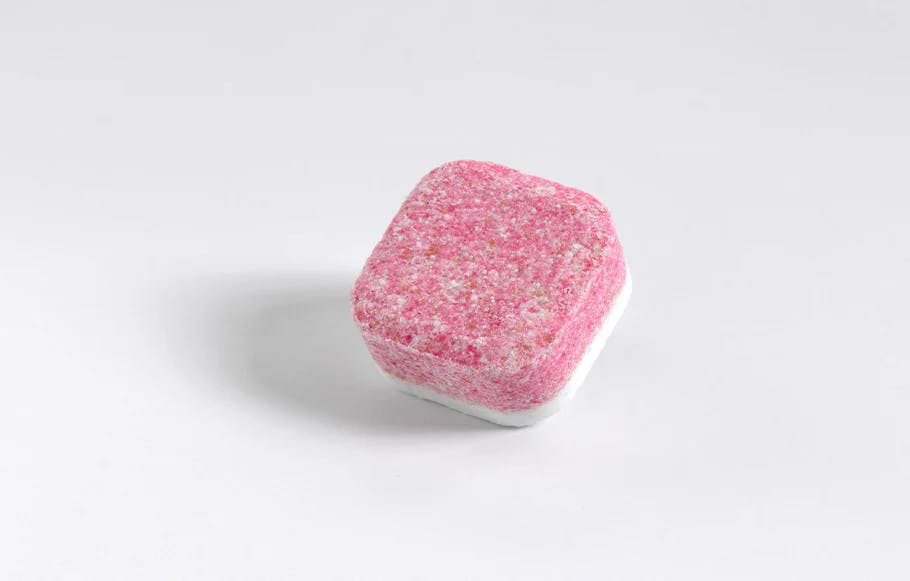 ein rosa smol Geschirrspültab auf grauem Hintergrund