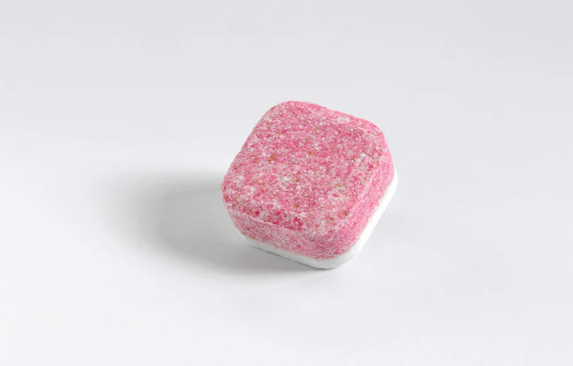 ein rosa smol Geschirrspültab auf grauem Hintergrund