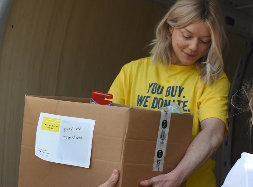hygiene bank worker passing a box of products out of a van