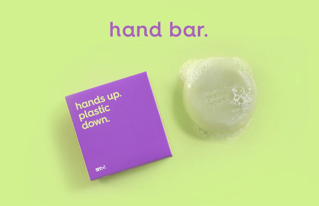 smol hand bar with suds alongside its purple packaging