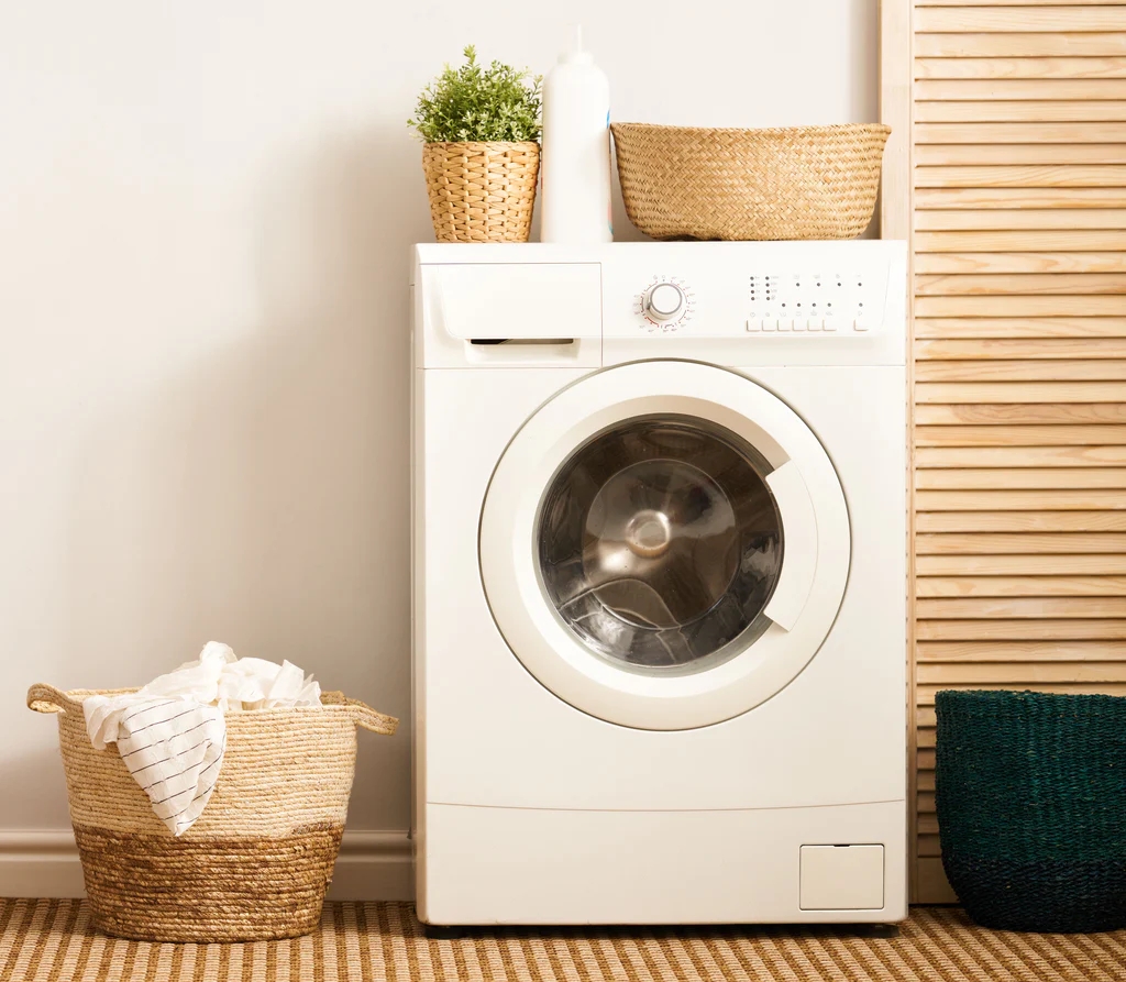 freestanding washing machine next to a basket of laundry