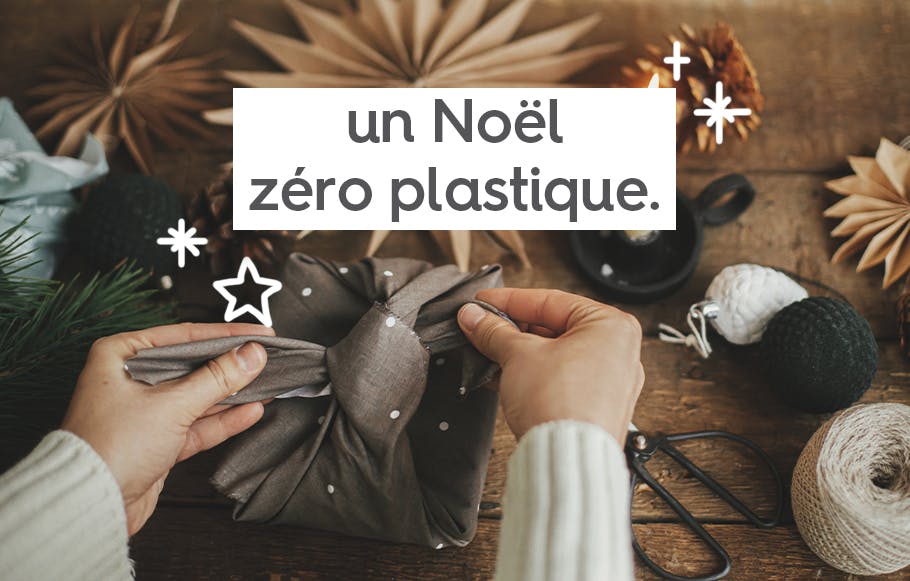 une paire de main emballant un cadeau sur une table en bois avec un morceau de tissu.