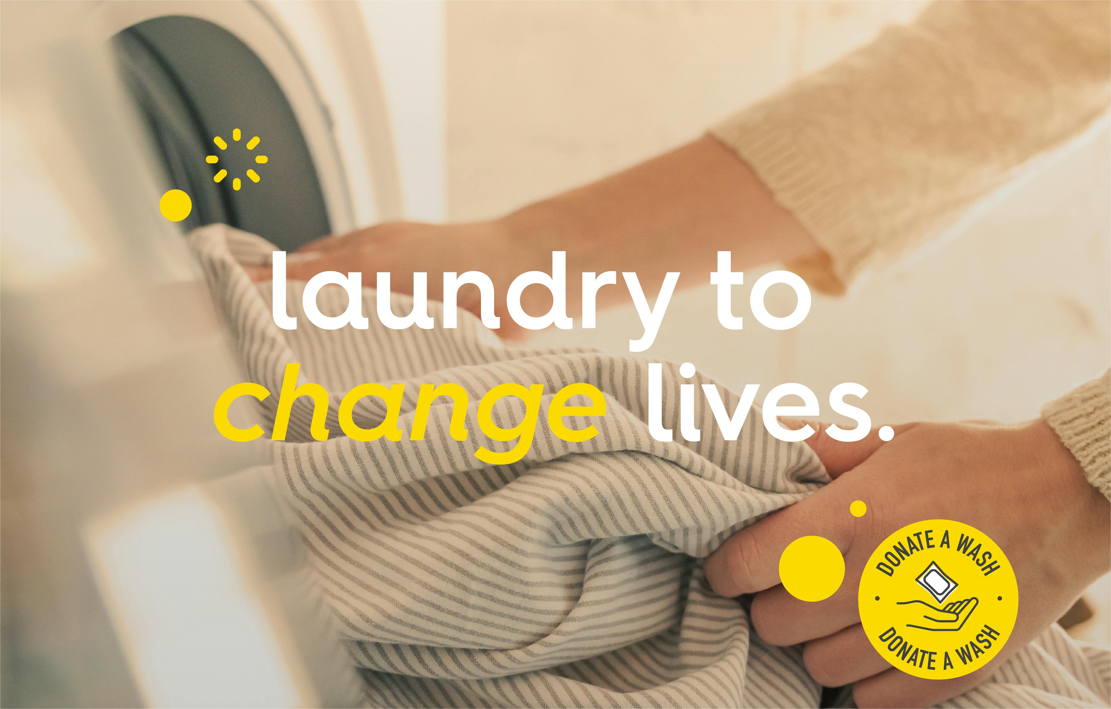 image of unloading laundry machine with illustration of bubbles and donate a wash logo, text: laundry to change lives. 