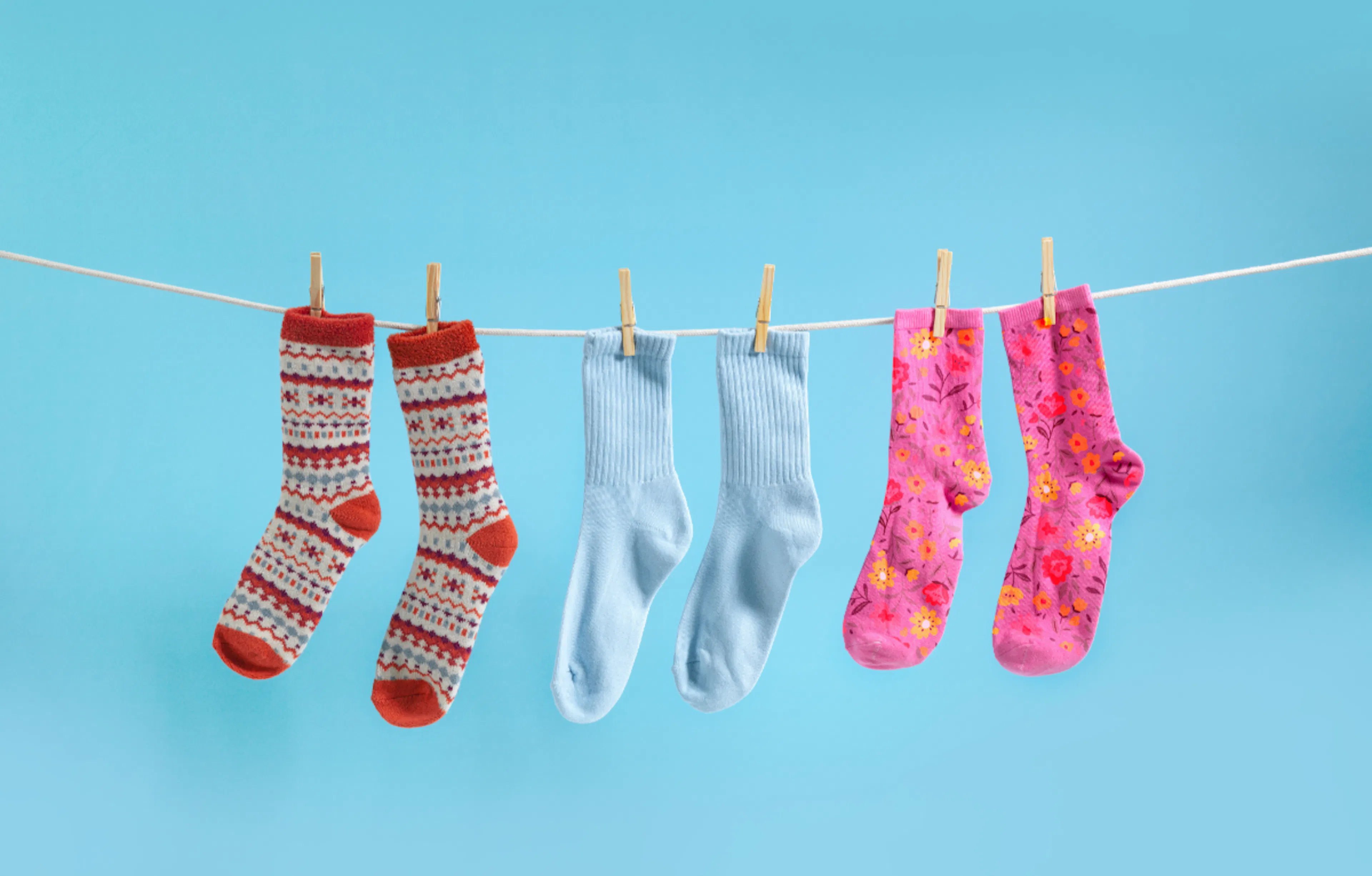 socks hanging on a washing line against a blue backdrop