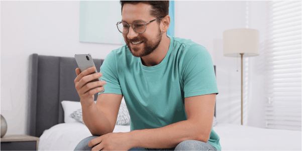 Man sitting on bed checking phone 