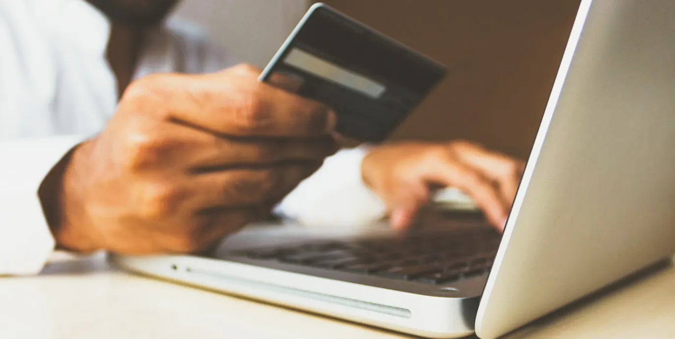 person using laptop computer holding a credit card