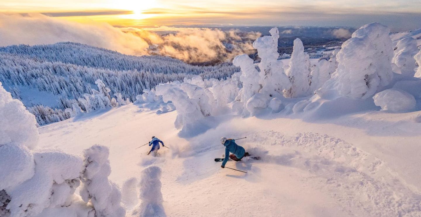 Two skiers hitting the twilight slopes at Sun Peaks in British Columbia, Canada.