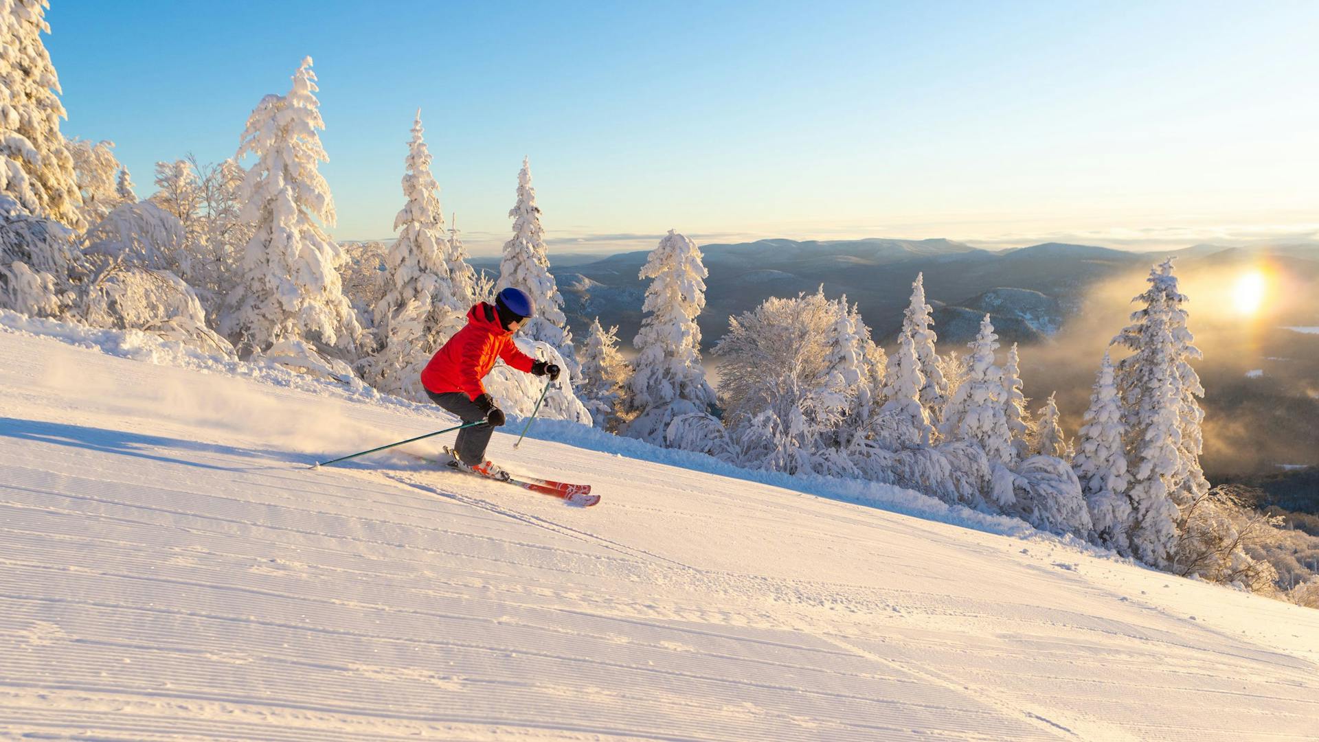 Skier of undiscernible gender in orange ski jacket skiing the slopes of Mont Tremblant in Quebec, Canada, near the East Coast of the United States.