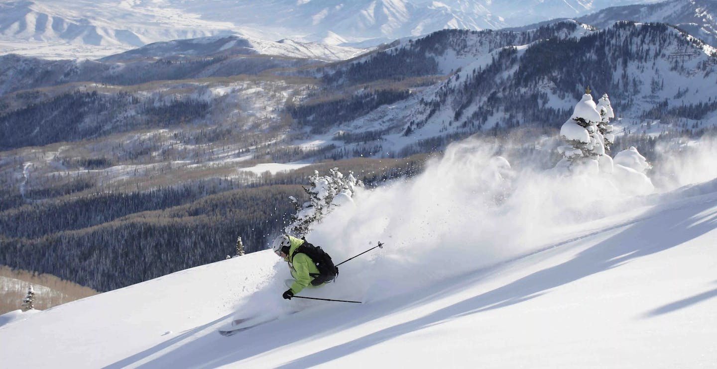Skier of undiscernible gender in line green ski jacket hitting the slopes at Brighton Resort in Brighton, Utah, USA, near Salt Lake City.