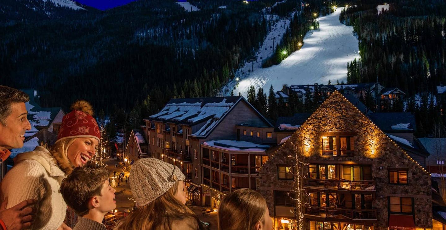 Family on the balcony of their hotel room gazing out upon the slopes of Keystone in Colorado, USA, near Denver.