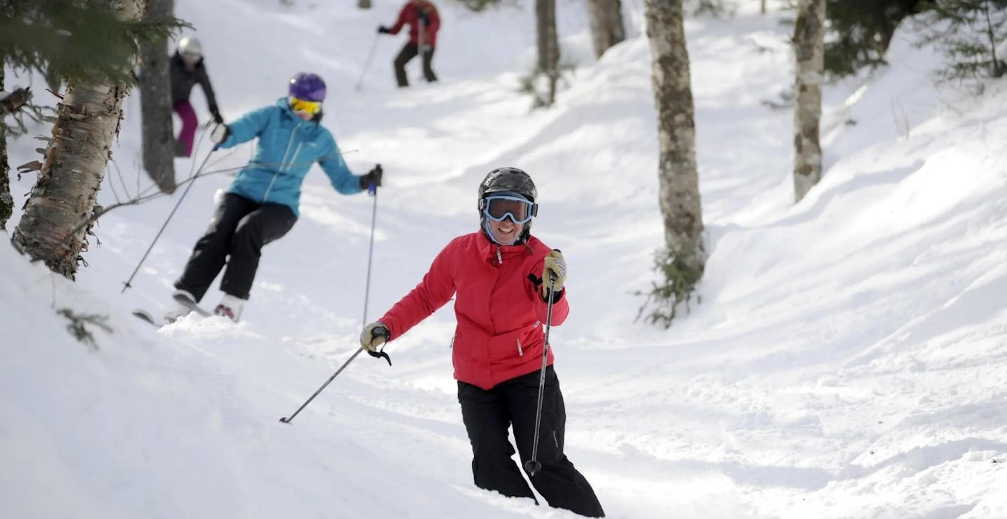 Four skiers in colorful ski attire hitting the slopes at Sugarbush Resort in Vermont, USA.