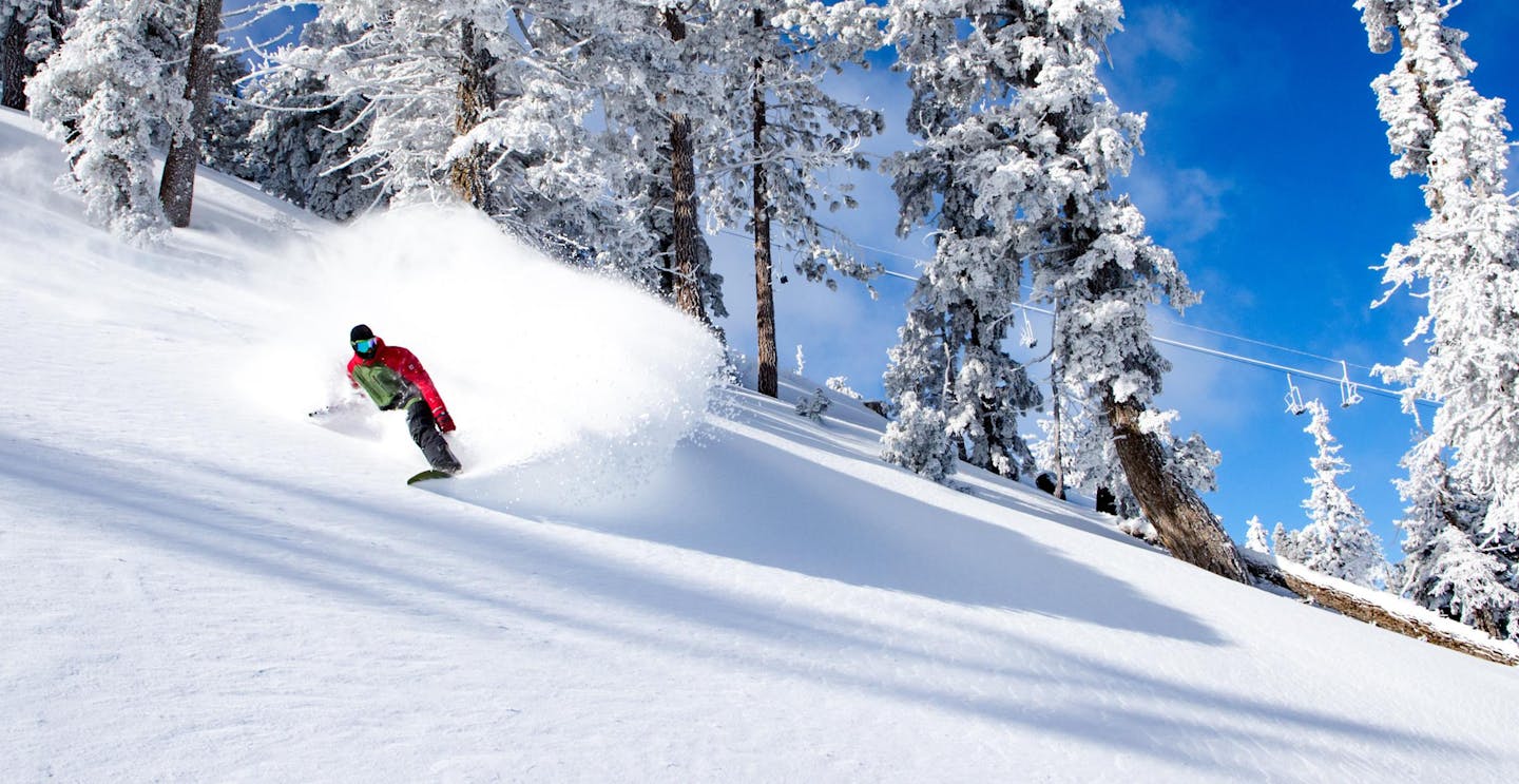 Male skier in red and black ski attire hitting the slopes at Snow Summit in California, USA, near Los Angeles.