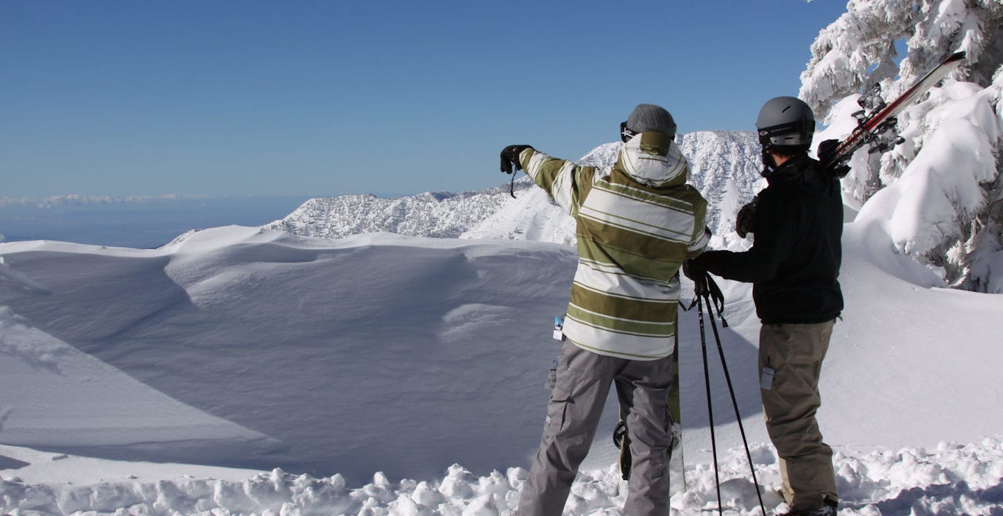 Two male skiers taking in the views on the summit of Mountain High in California, USA, near Los Angeles.