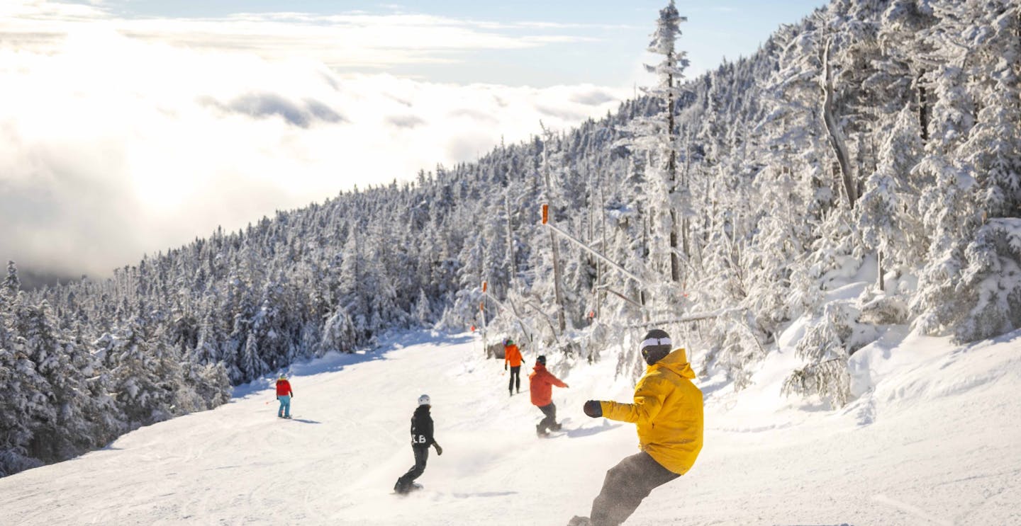 Five snowboarders in colorful ski attire hitting the slopes at Whiteface in New York, USA.