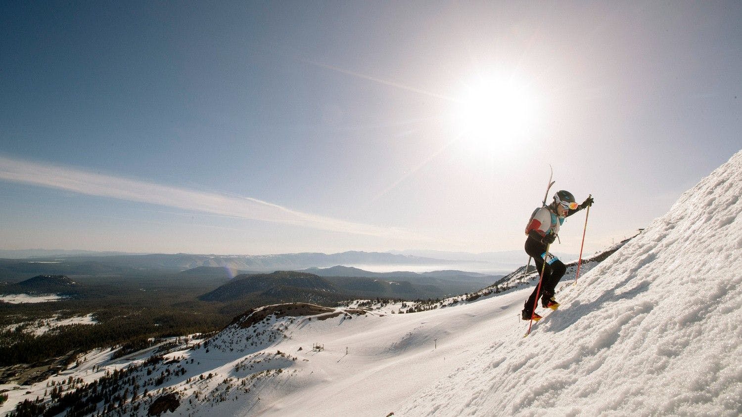 Male skier in black, white and red ski attire uphilling at Mammoth Mountain near Los Angeles in California, USA.