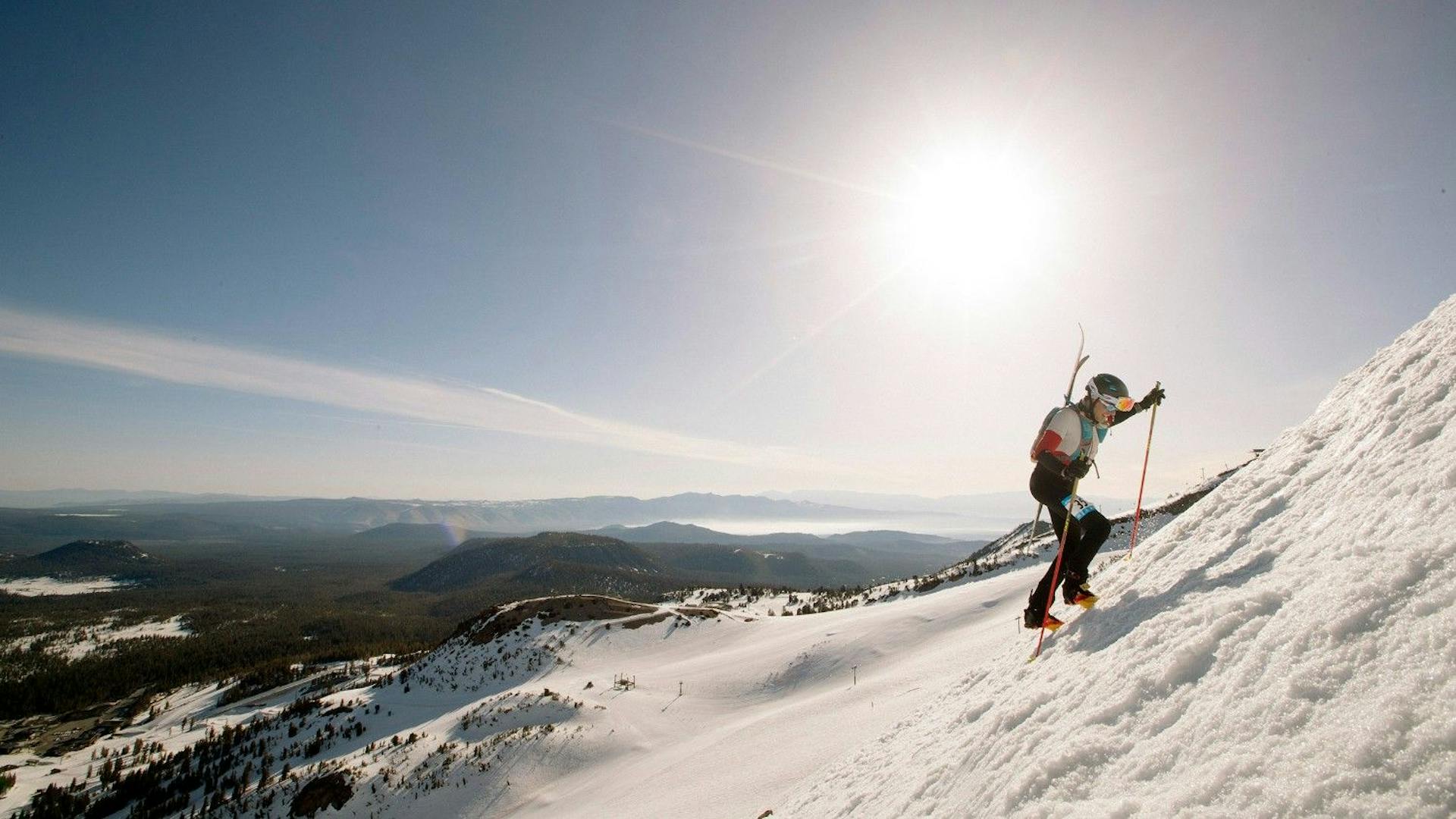Male skier in black, white and red ski attire uphilling at Mammoth Mountain near Los Angeles in California, USA.