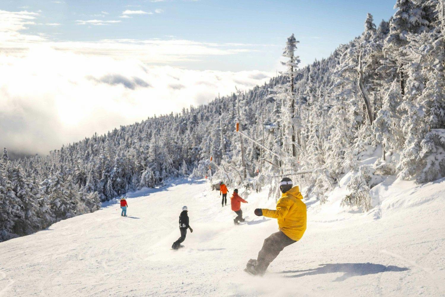 Five snowboarders in colorful ski attire hitting the slopes at Whiteface in New York, USA.