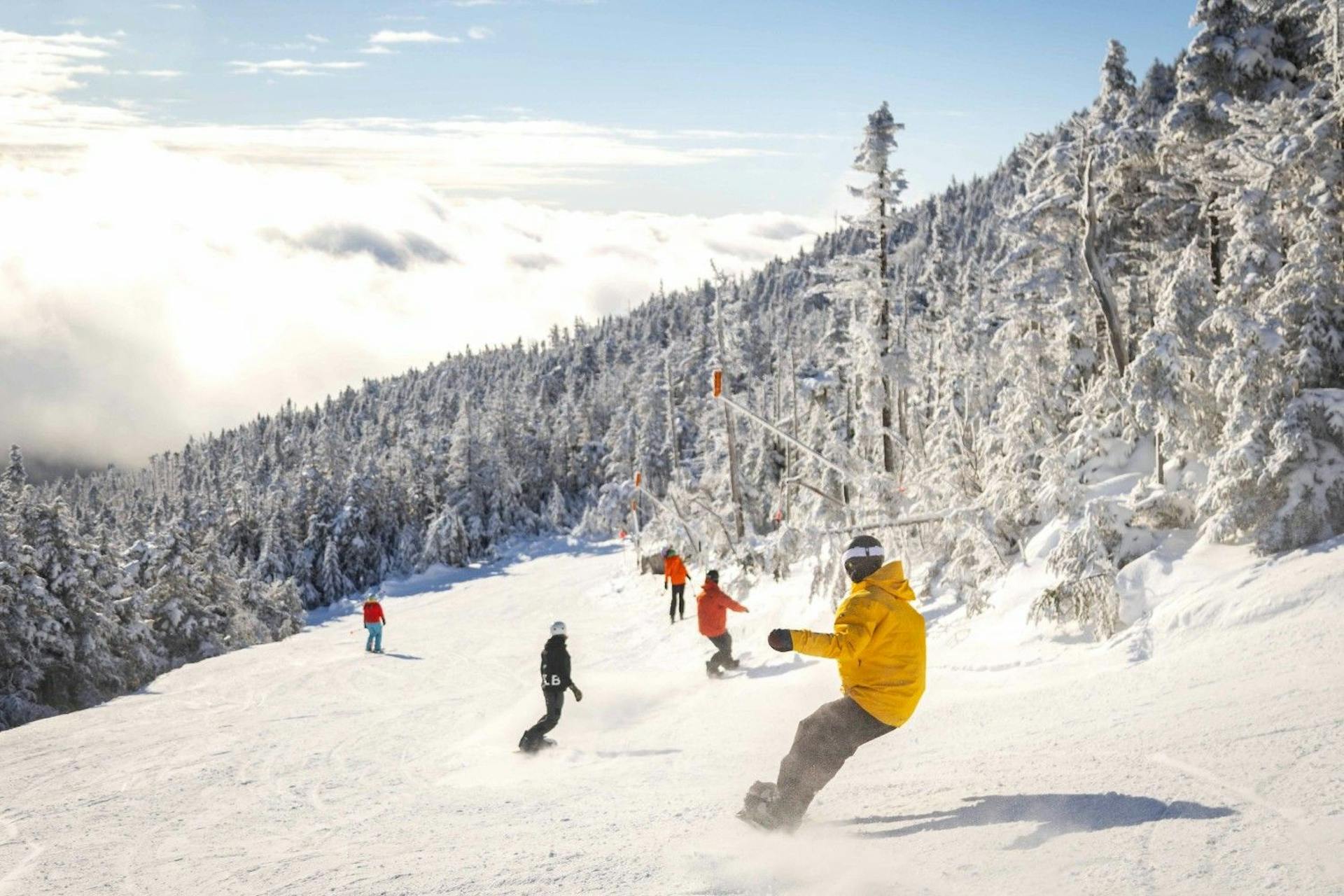 Five snowboarders in colorful ski attire hitting the slopes at Whiteface in New York, USA.