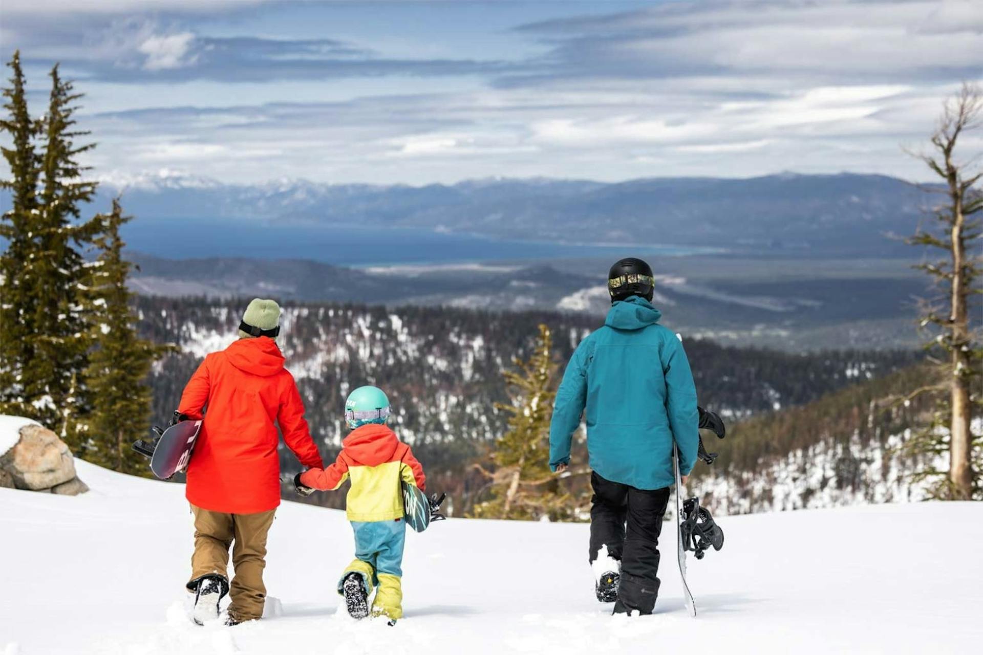 Family of snowboarders in colorful snowboarding attire descending the slopes at Sierra-at-Tahoe near Lake Tahoe in California, USA.