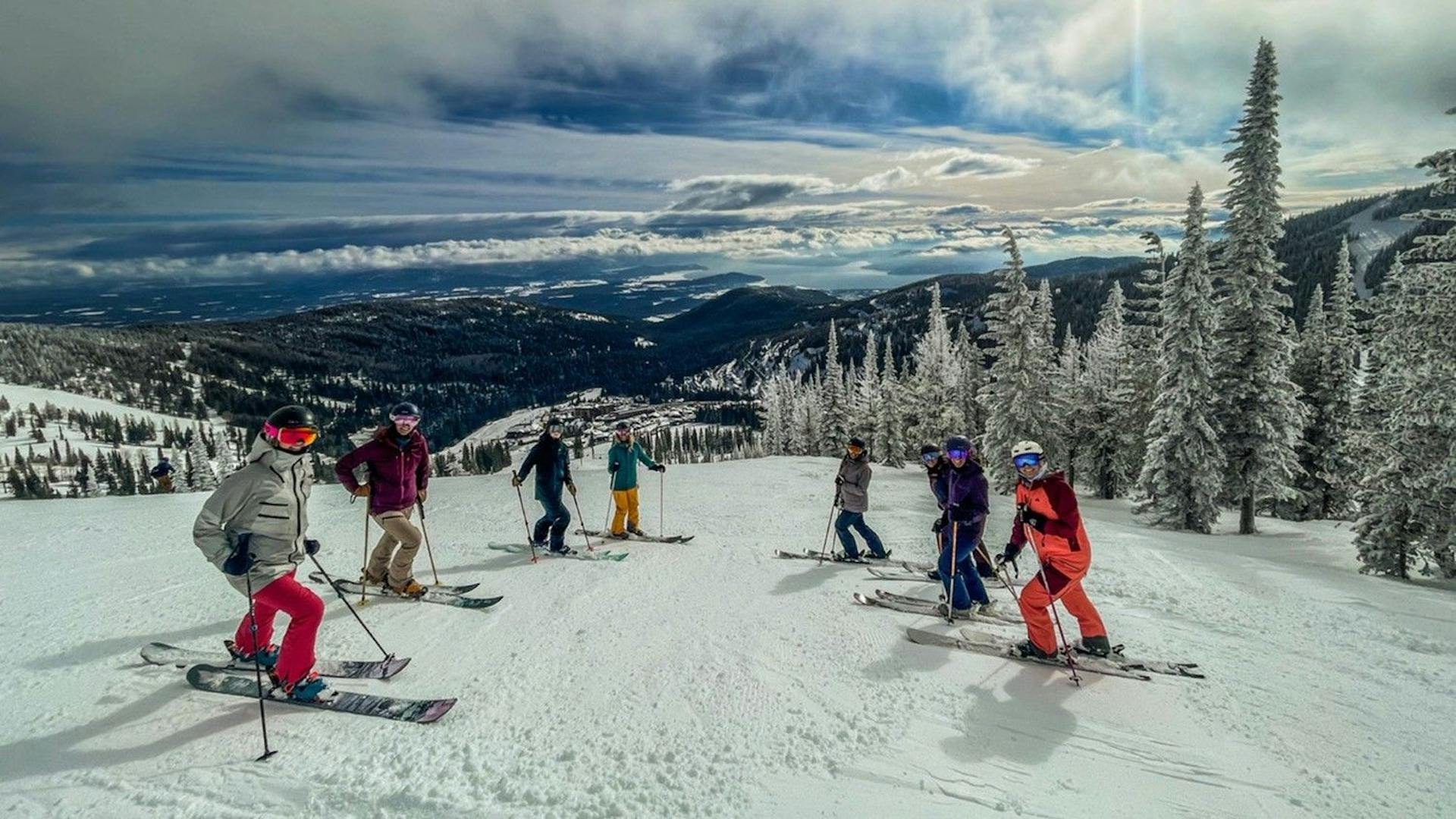Seven diverse skiers in colorful ski attire hitting the slopes at Schweitzer Mountain Resort in Idaho, USA.