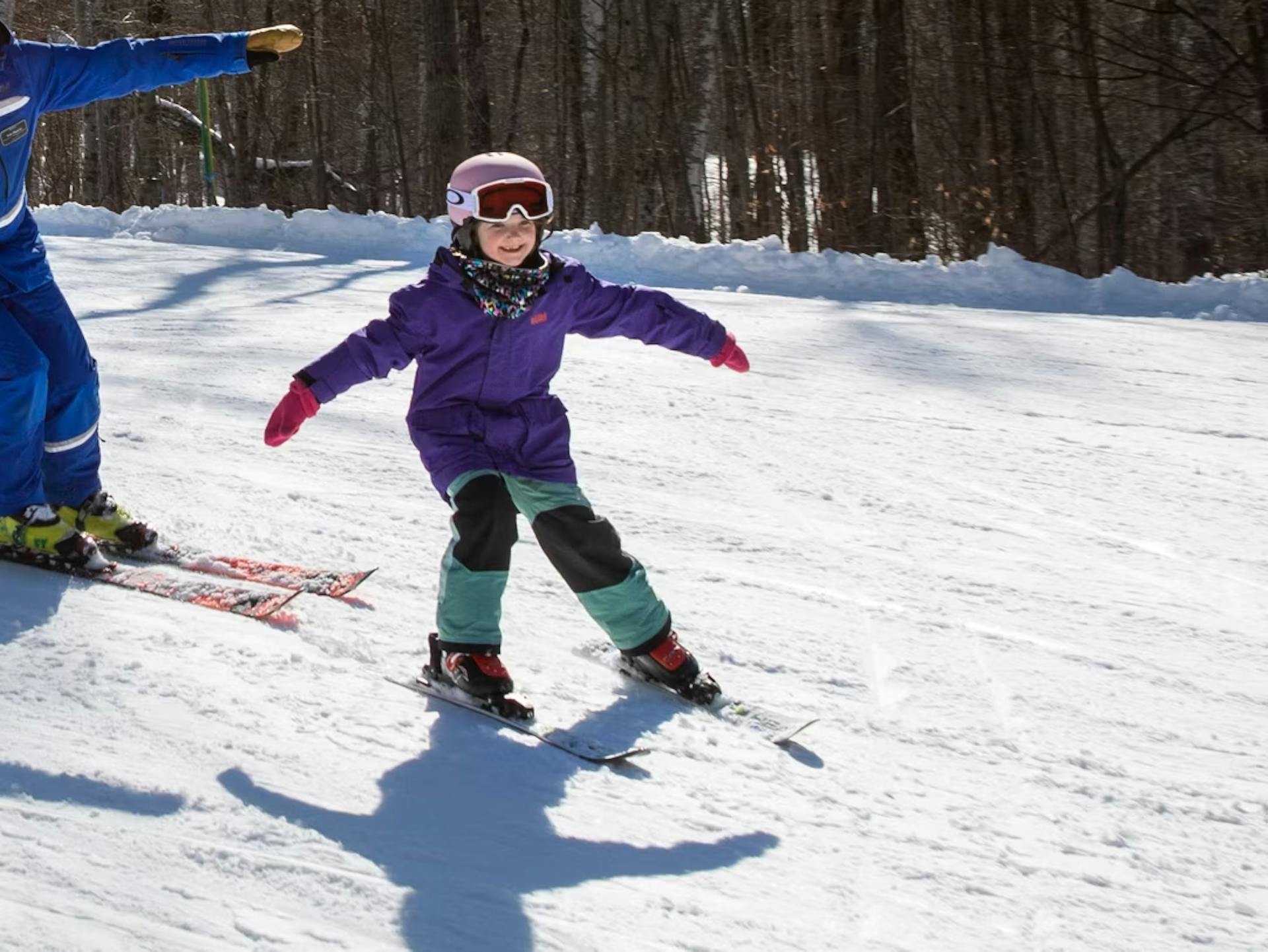 Skier of undiscernible gender in purple ski jacket and teal and black ski pants hitting the slopes at Mount Sunapee near Boston, Massachusetts, in New Hampshire, USA.