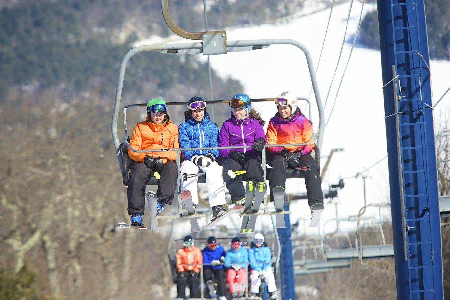 Eight diverse adult skiers in colorful ski attire riding the chairlift at Wachusett Mountain near Boston, Massachusetts, in New Hampshire, USA.