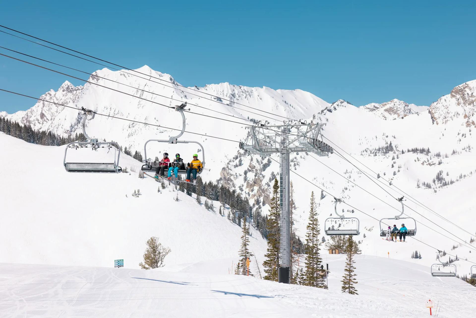 Chairlifts running with skiers seated at Alta Ski Area near Salt Lake City in Utah, USA.