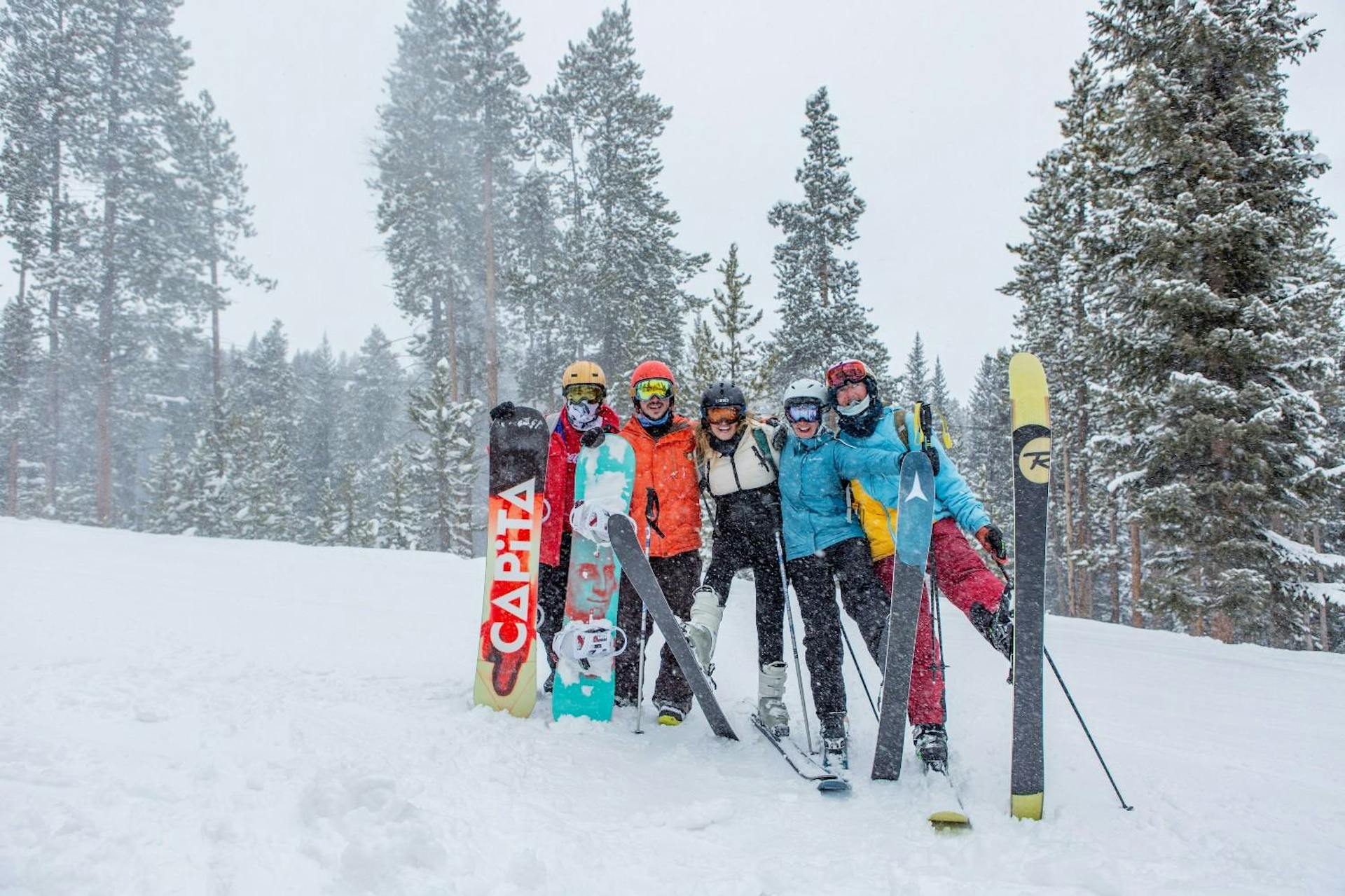 Group of five skiers and snowboarders huddling together to take a photo on the slopes of Vail in Colorado, USA.