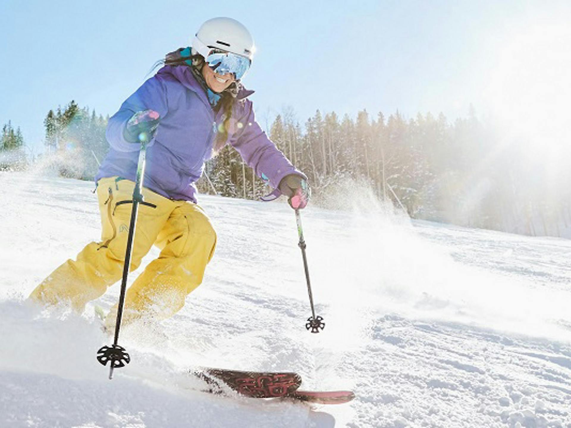 Female skier in purple and yellow ski attire hitting the slopes at Keystone Ski Resort in Colorado, USA.