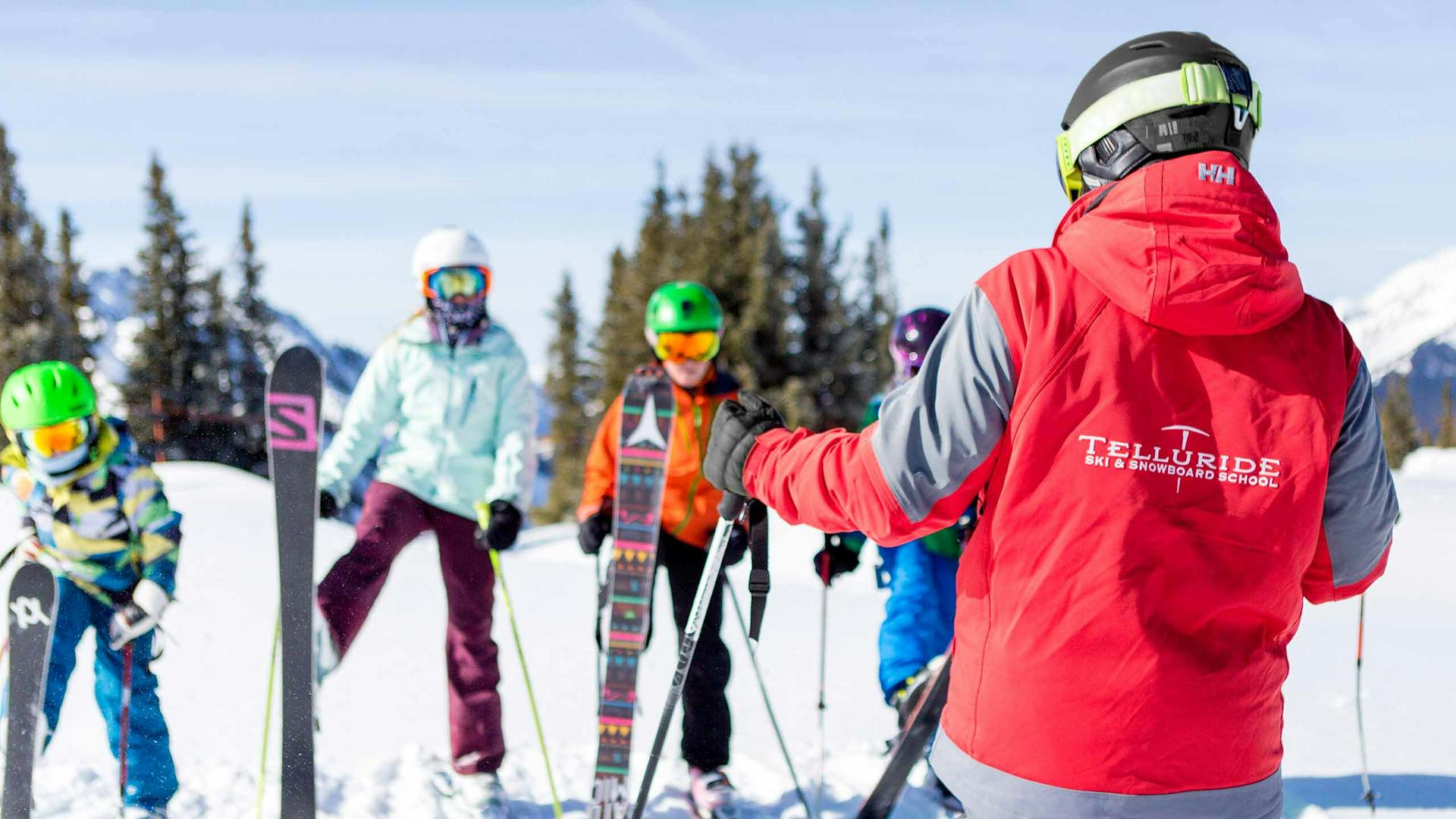 Telluride Ski Resort ski instructor of undiscernible gender in red and grey ski jacket imparting a lesson to a special needs class at Telluride Ski Resort in Colorado, USA.