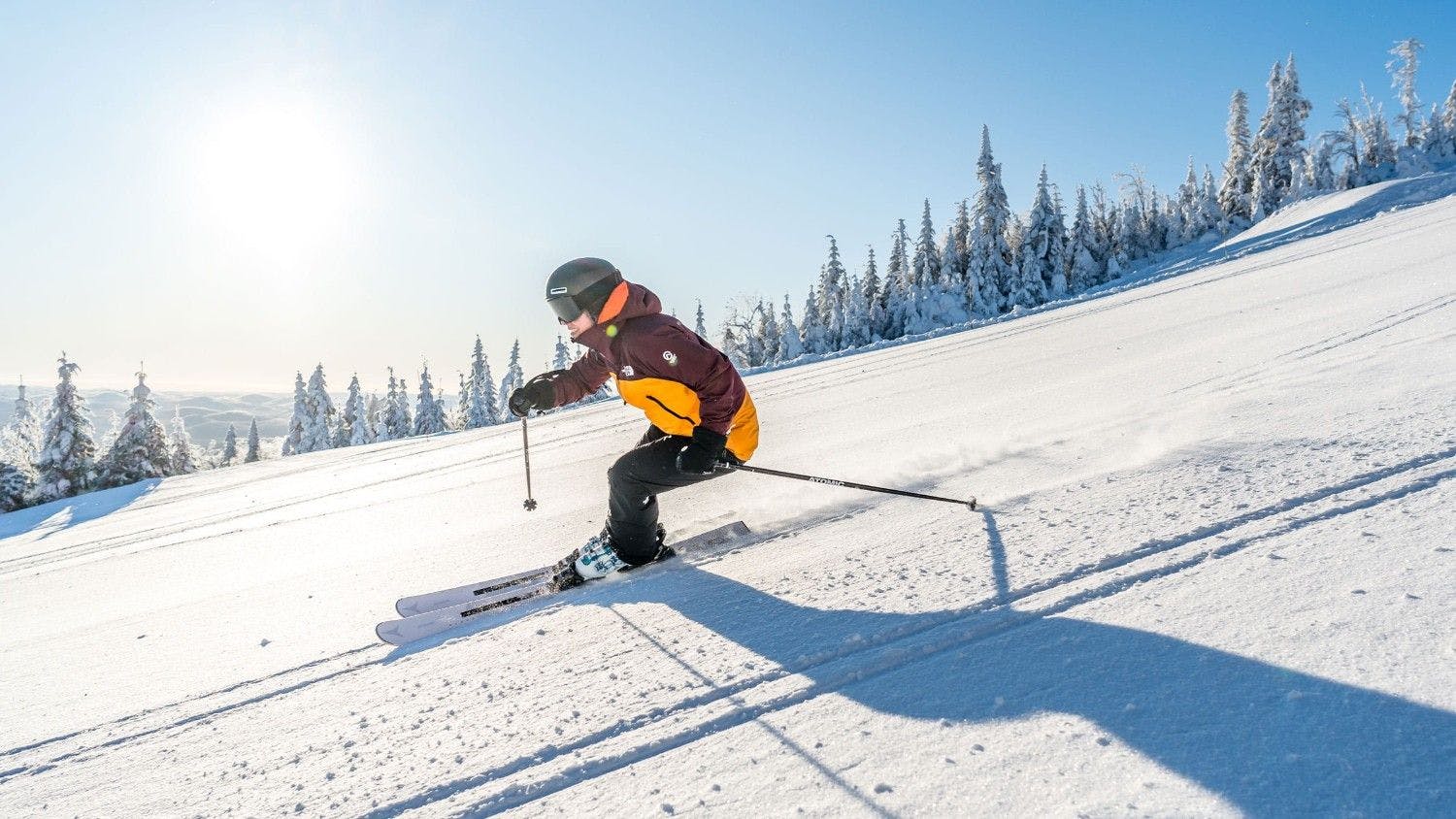 Skier of undiscernible gender in brown and yellow ski attire hitting the slopes at Mont Tremblant in Quebec, Canada.