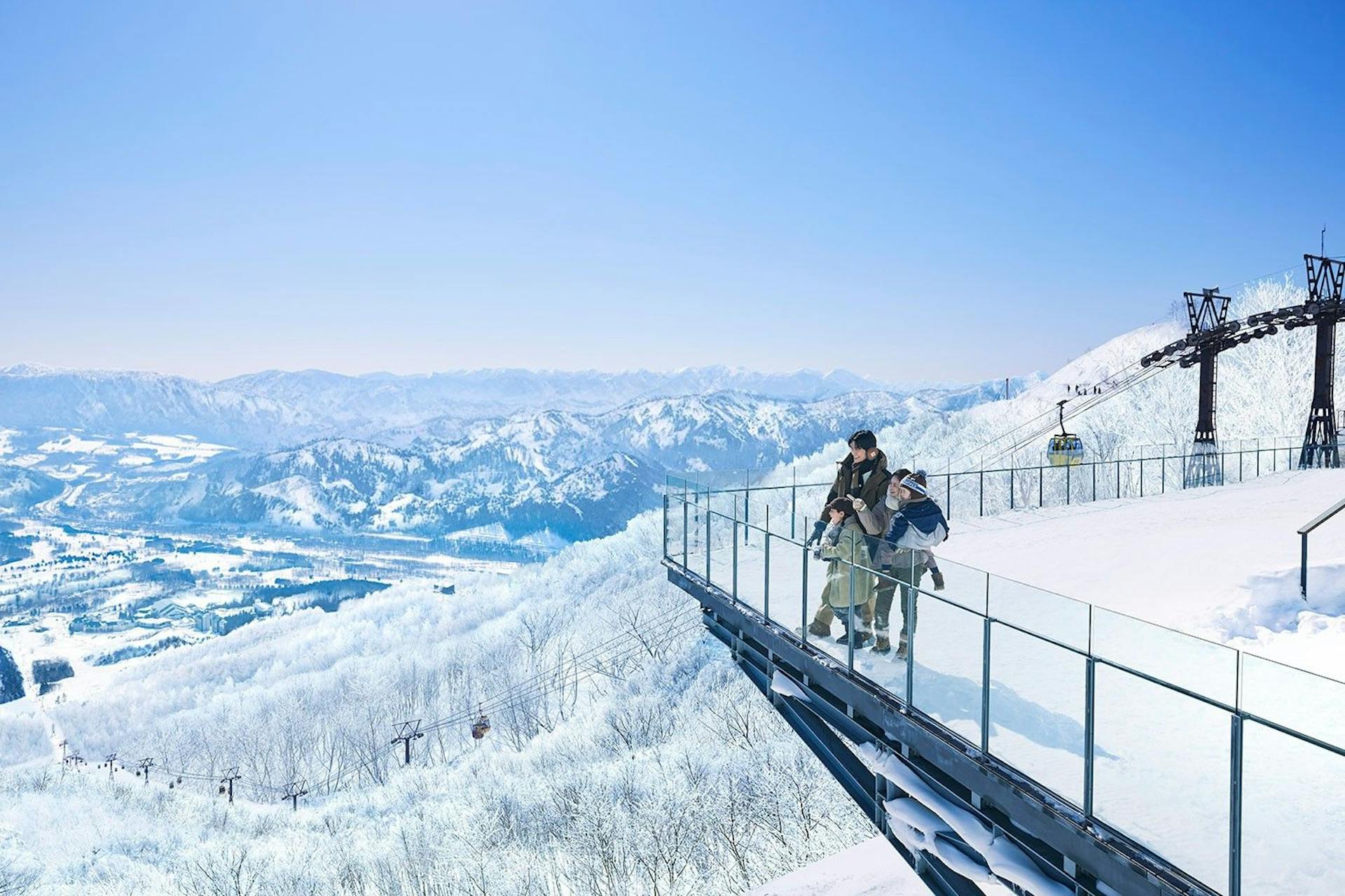 Asian heterosexual couple with two children gazing at the slopes of Tomamu from the terrace of Hoshino Resorts in Hokkaido, Japan.
