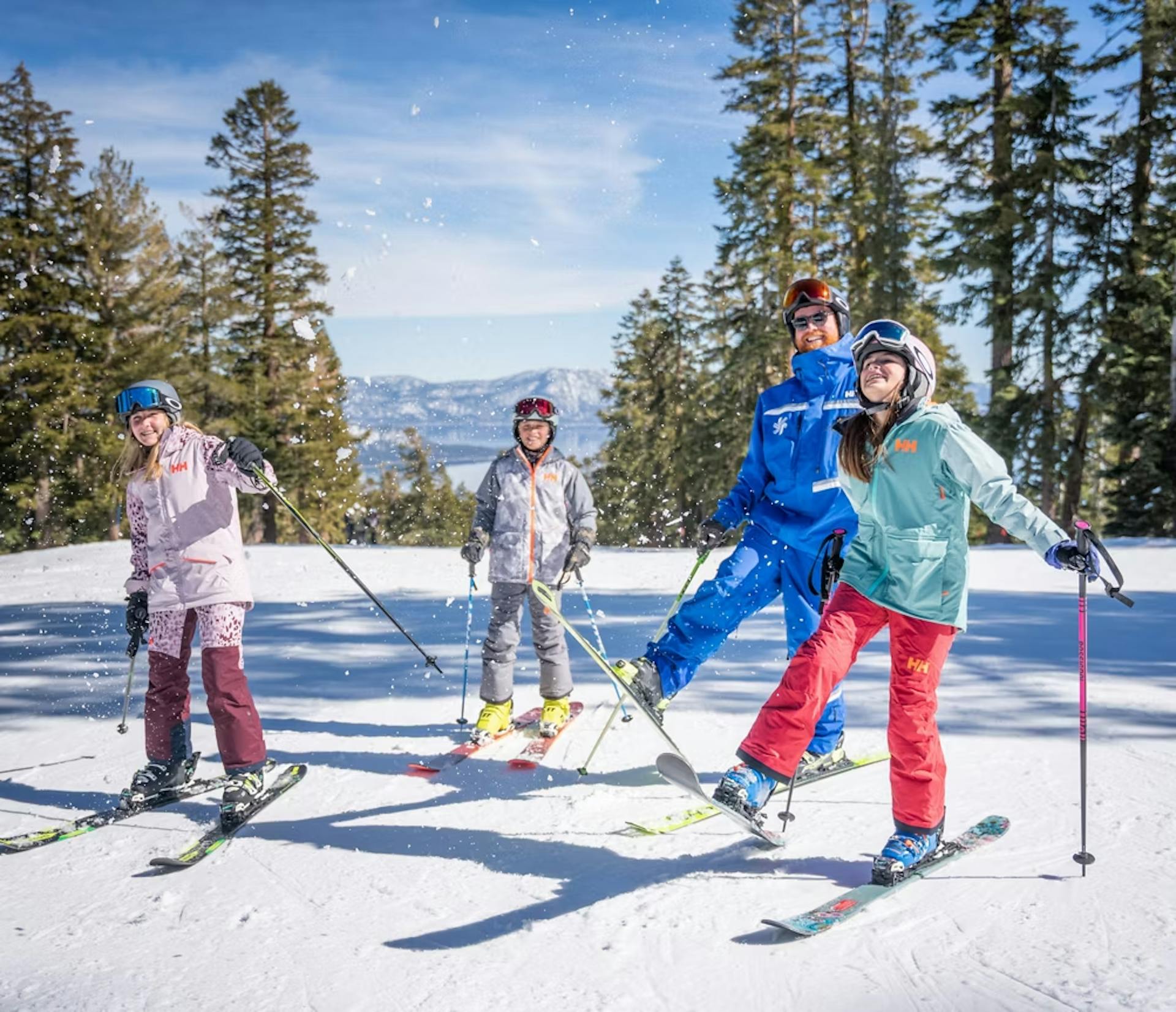 Three young white female skiers in colorful ski attire with an older white male skier with red beard and blue ski attire hitting the slopes at Northstar California Resort in California, USA.