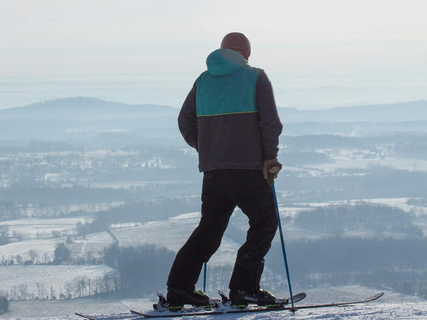 Male skier in teal and gray ski jacket taking in the view from the slopes at Liberty Mountain Resort near Washington, D.C., USA.
