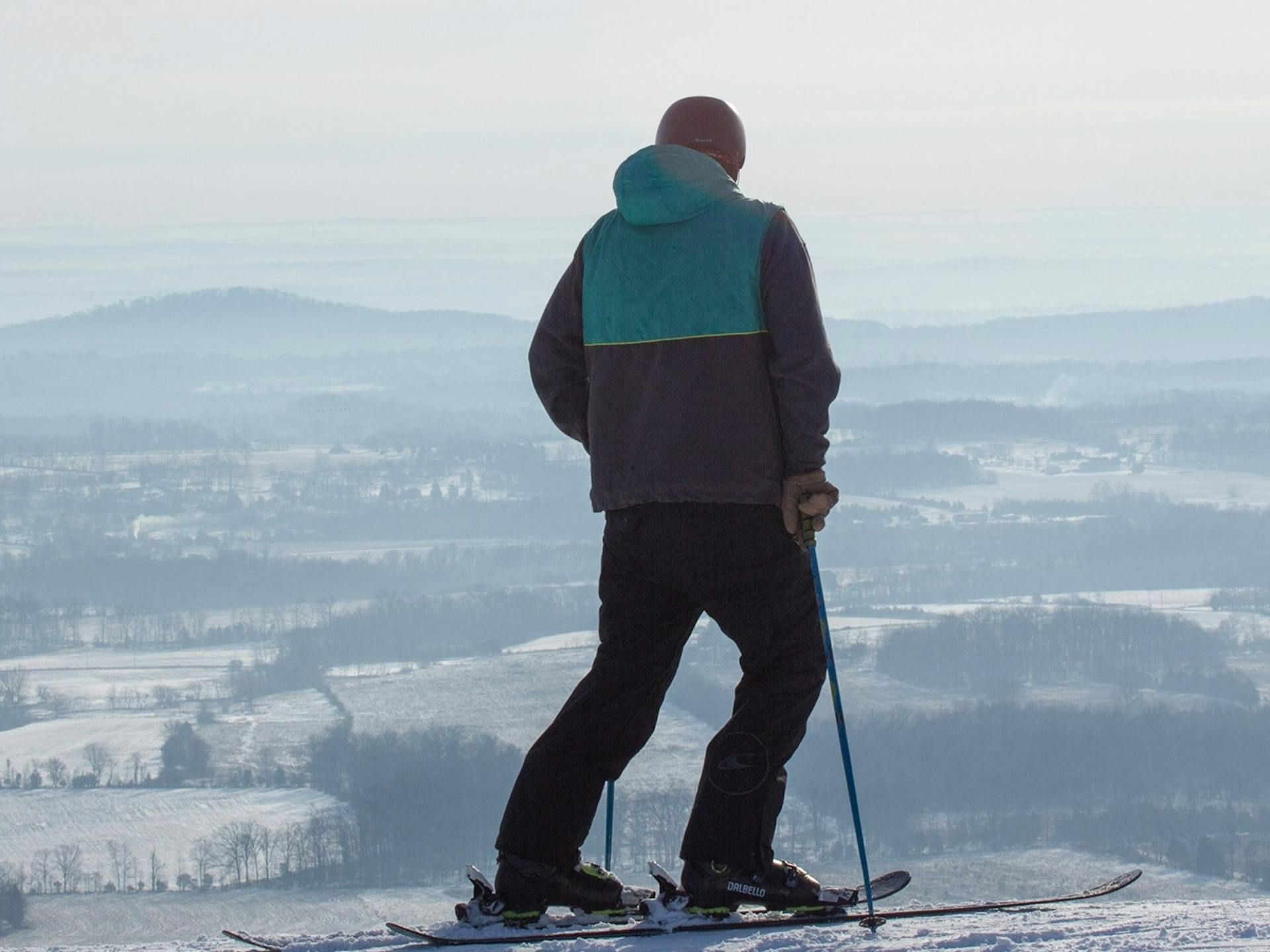 Male skier in teal and gray ski jacket taking in the view from the slopes at Liberty Mountain Resort near Washington, D.C., USA.