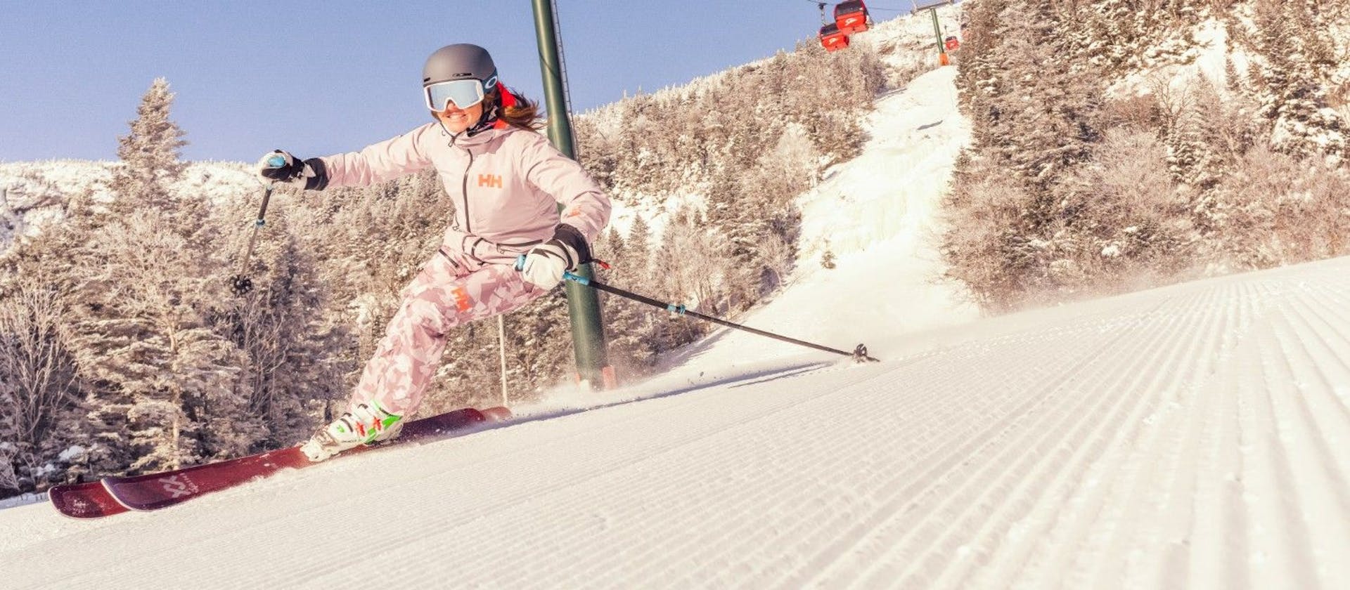 Female skier in pink ski attire hitting the slopes at Stowe Mountain Resort in Vermont, USA.