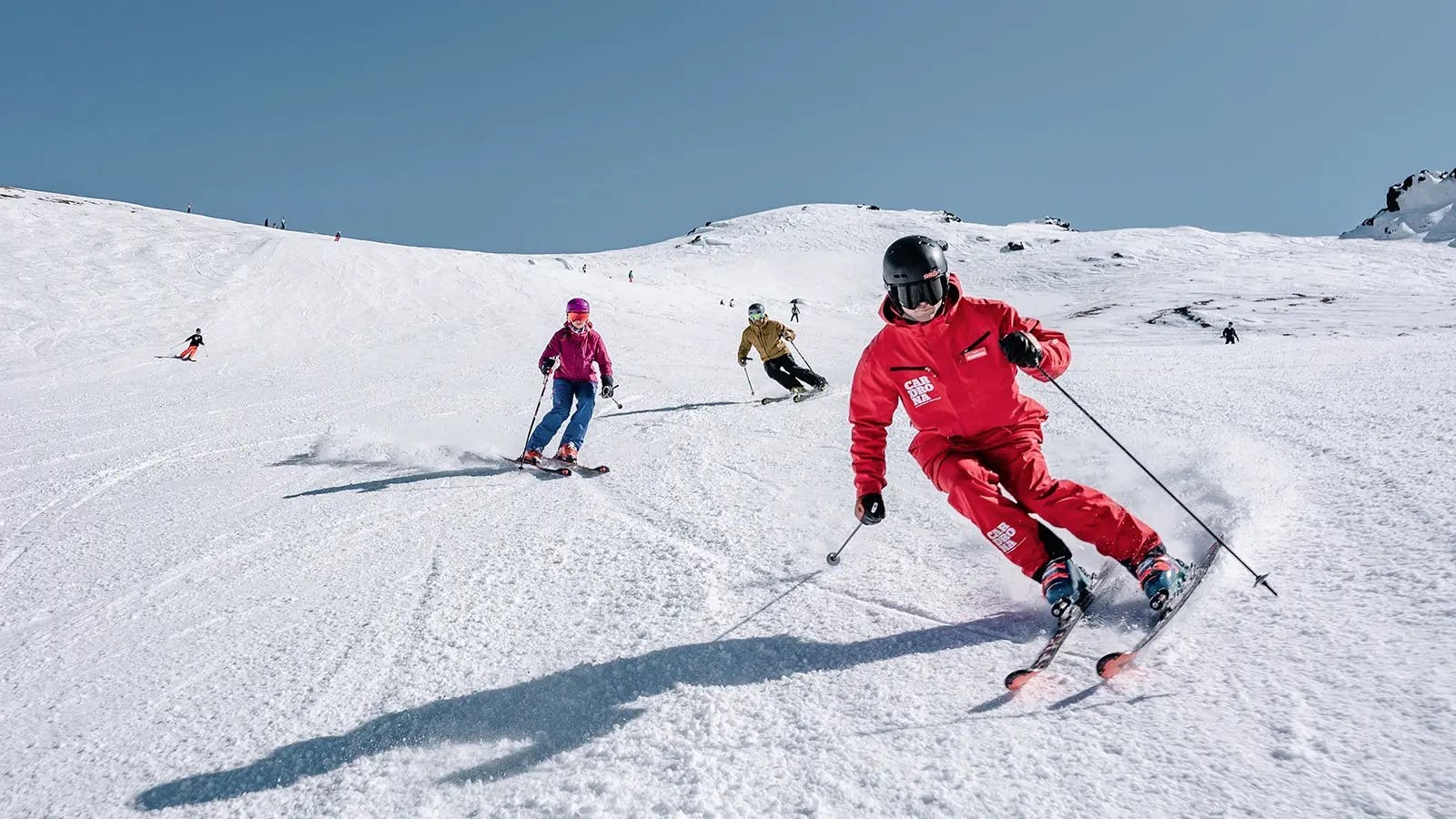 Three diverse skiers in brightly-colored ski attire hitting the slopes at Cardrona in New Zealand.