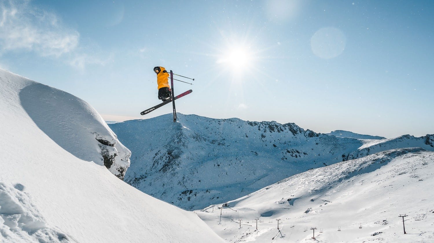 Skier of undiscernible gender in yellow ski jacket hitting the slopes at The Remarkables in New Zealand.