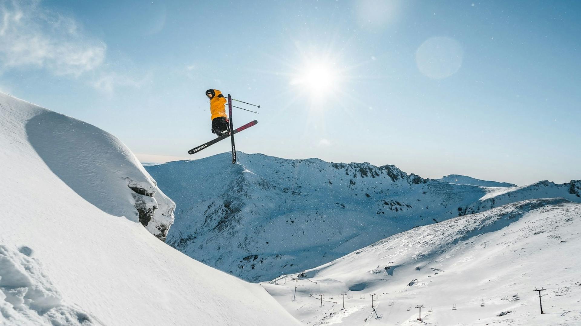 Skier of undiscernible gender in yellow ski jacket hitting the slopes at The Remarkables in New Zealand.