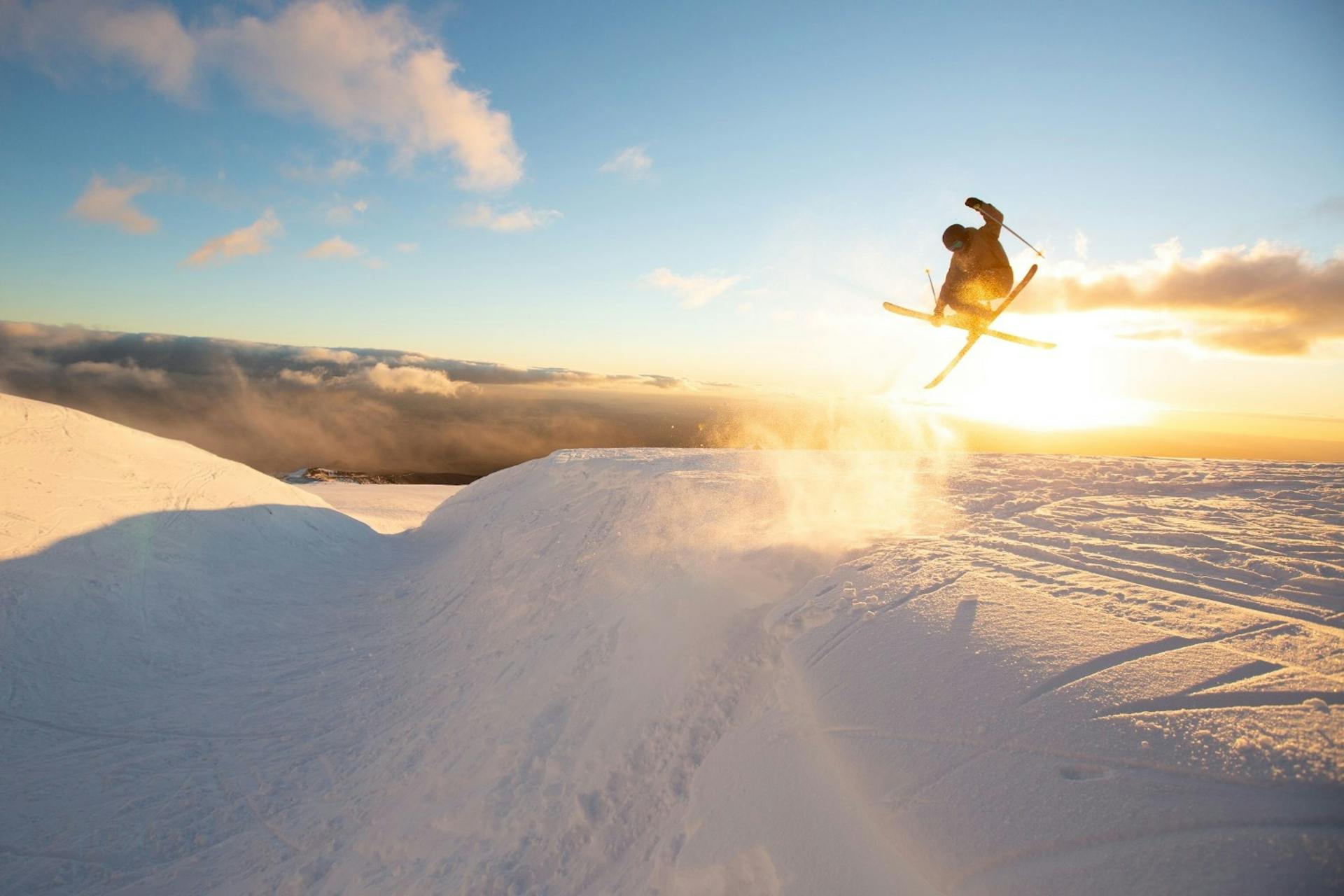 Skier of undiscernible gender in yellow ski attire hitting the slopes at Turoa in New Zealand.