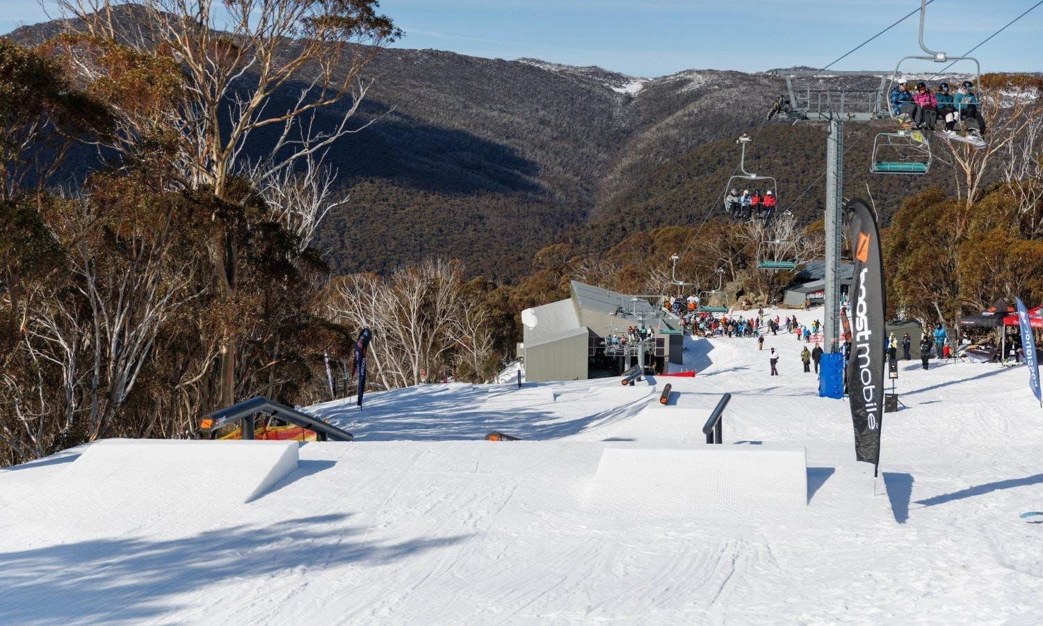 Chairlifts running with various skiers aboard next to the terrain park at Thredbo in Australia.