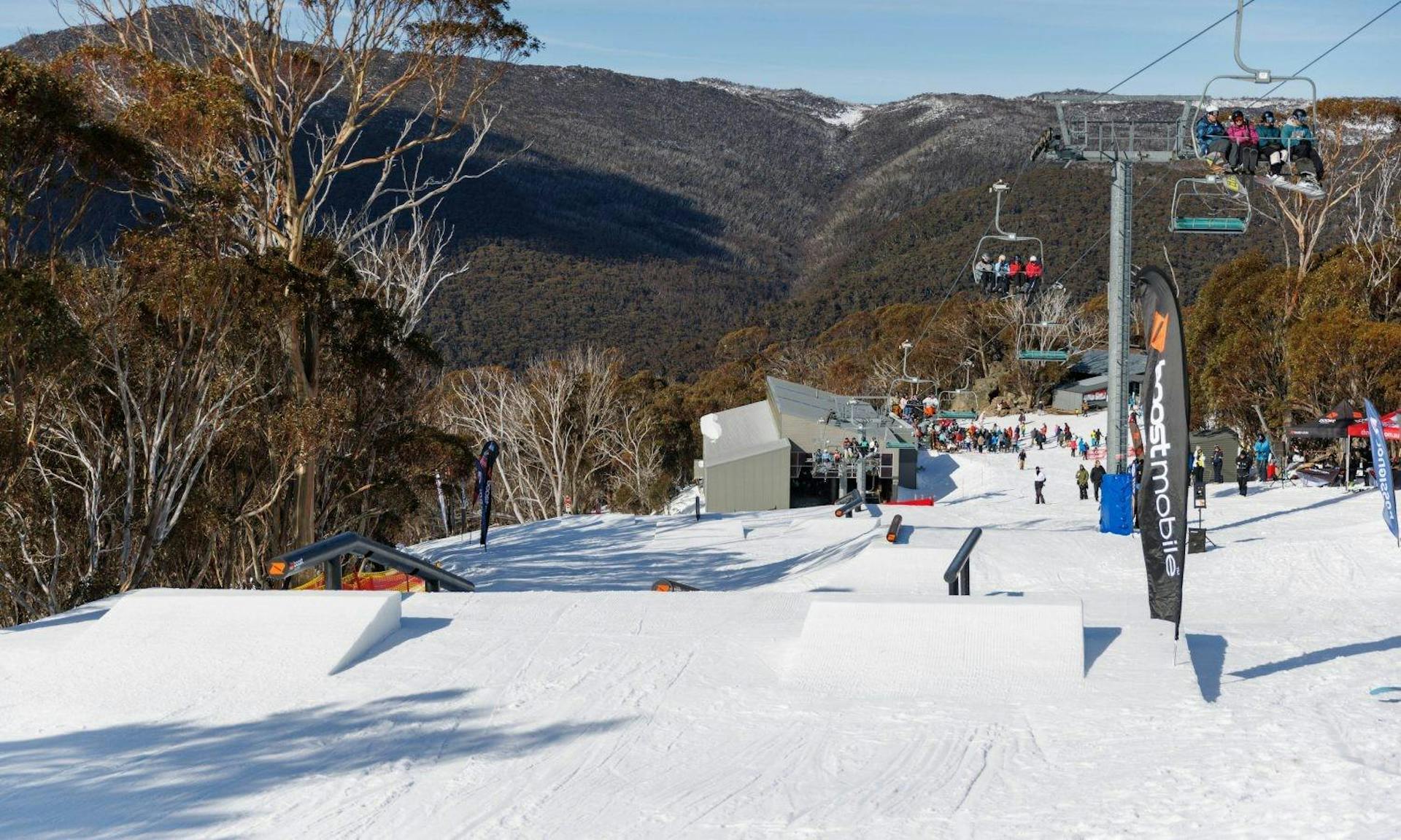 Chairlifts running with various skiers aboard next to the terrain park at Thredbo in Australia. 
